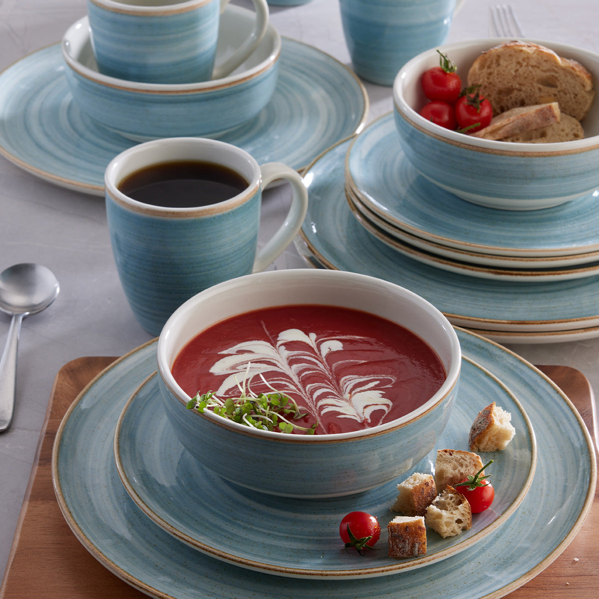Vajilla Corona Caoba Azul: platos, cerealeros y mugs en azul con borde marrón.