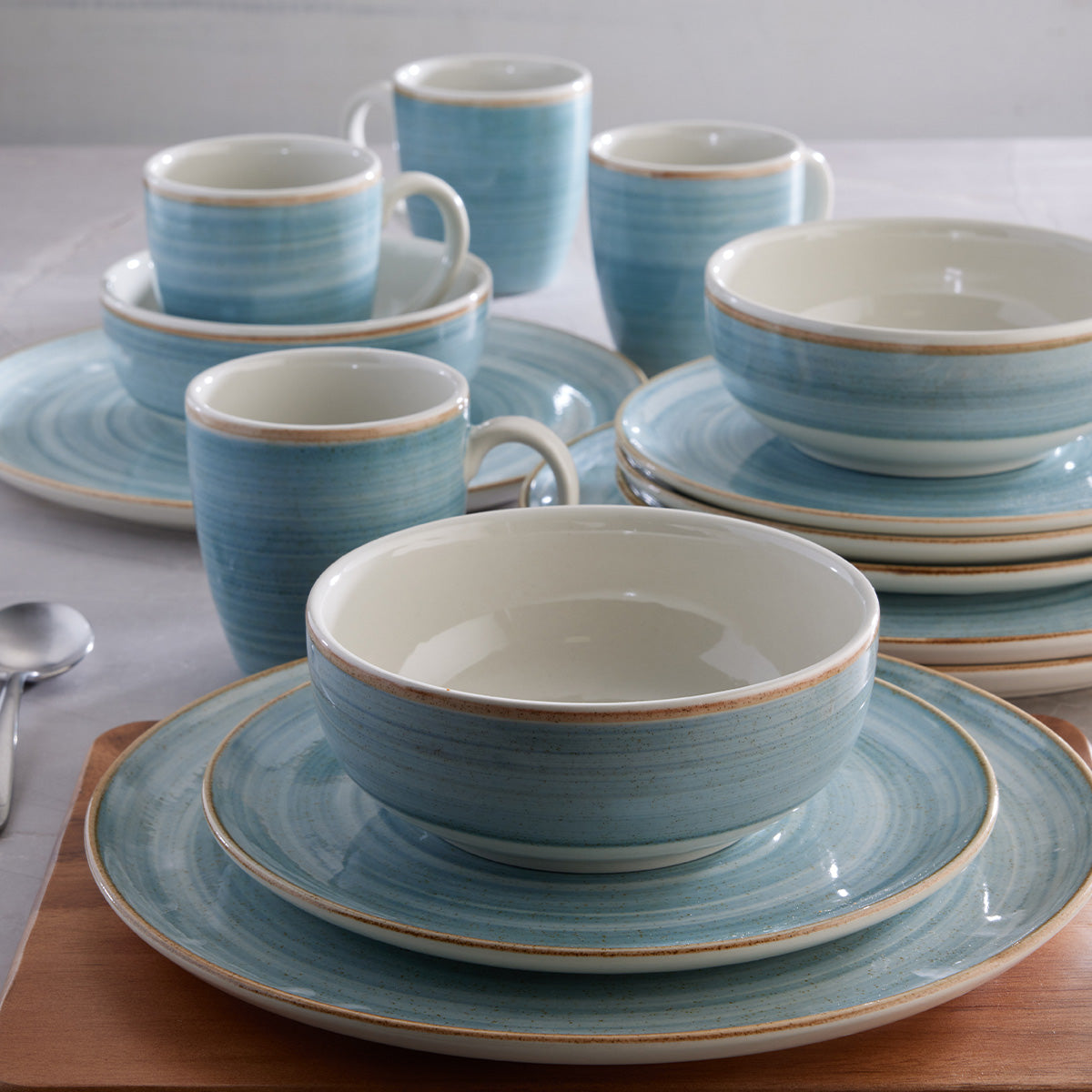 Vajilla Corona Caoba Azul: platos, cerealeros y mugs en azul con borde marrón.